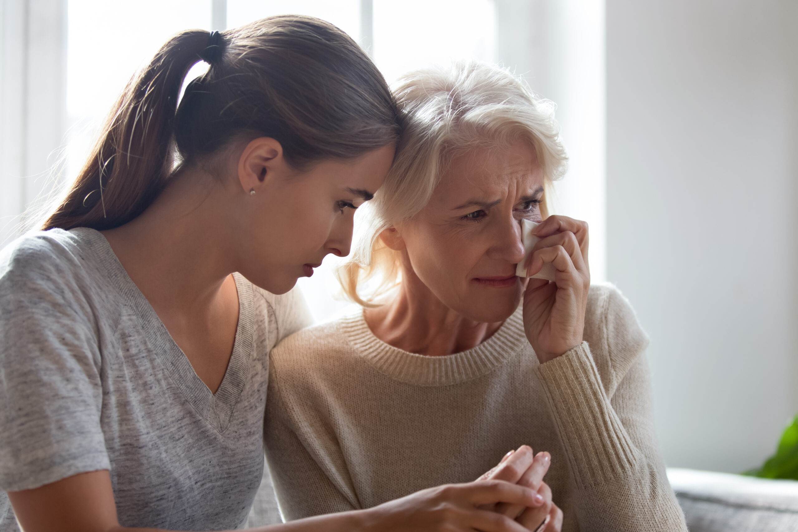 Loving adult female hug comfort caress crying elderly mother wipe tears use paper tissue, show support and care, depressed desperate mom and daughter feel sad unhappy mourning for family loss